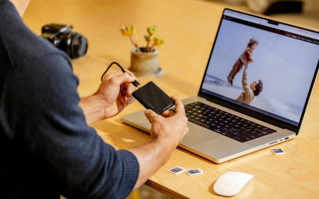 A man sitting at a table with a laptop and cell phone